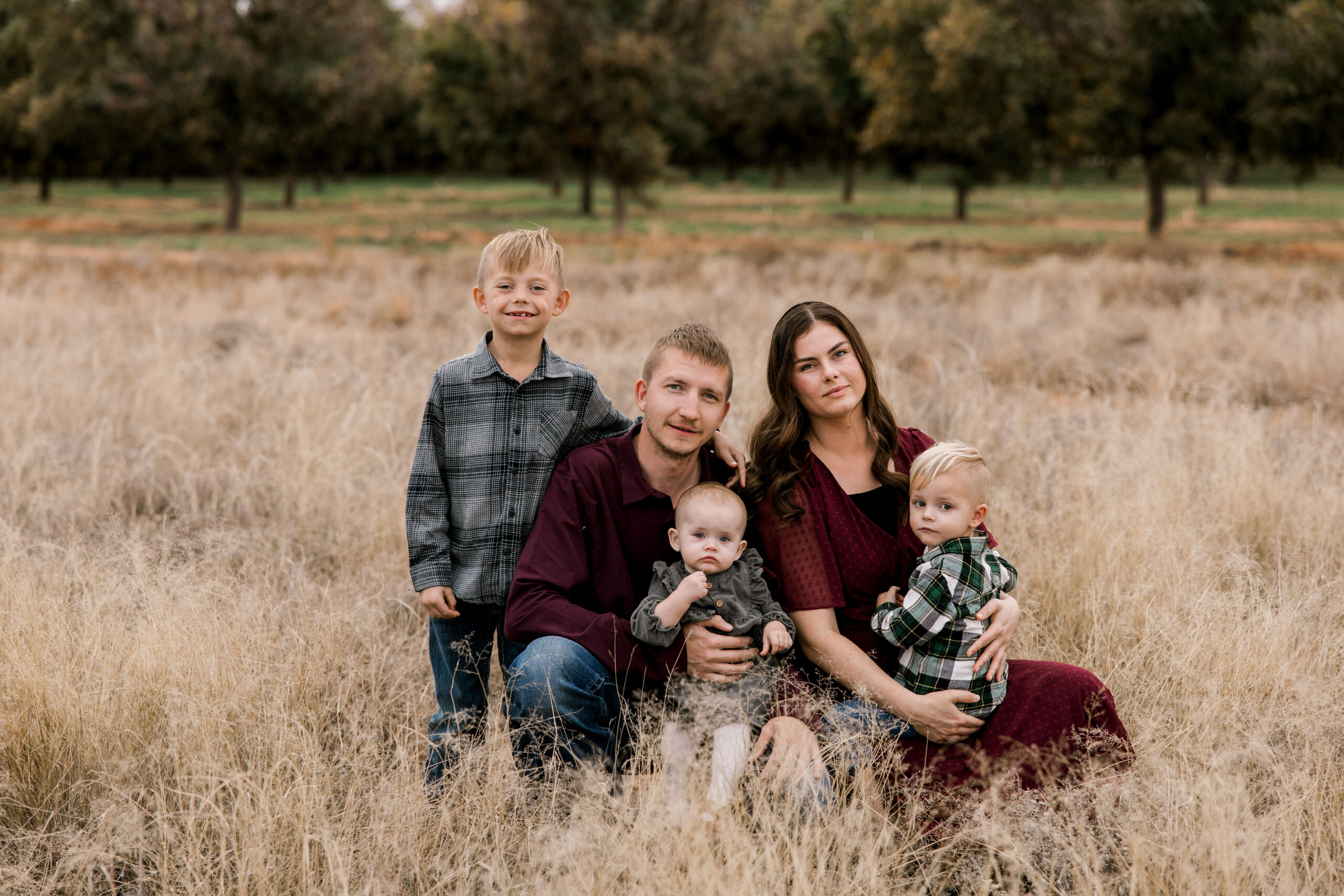 Family of 5 are sitting in a field for their fall family portraits. Captured by Mary Wiebe Photography.