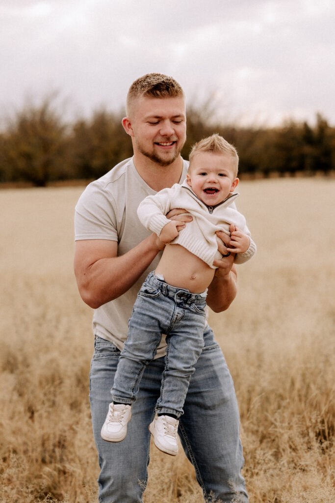 dad holding son in open field