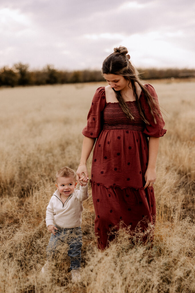 mom and son holding hands walking in open field as example of how to feel at ease in front of the camera