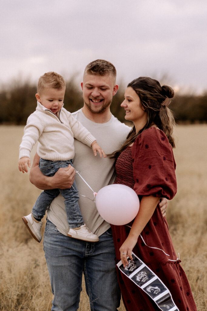 couple holding their son in open field
