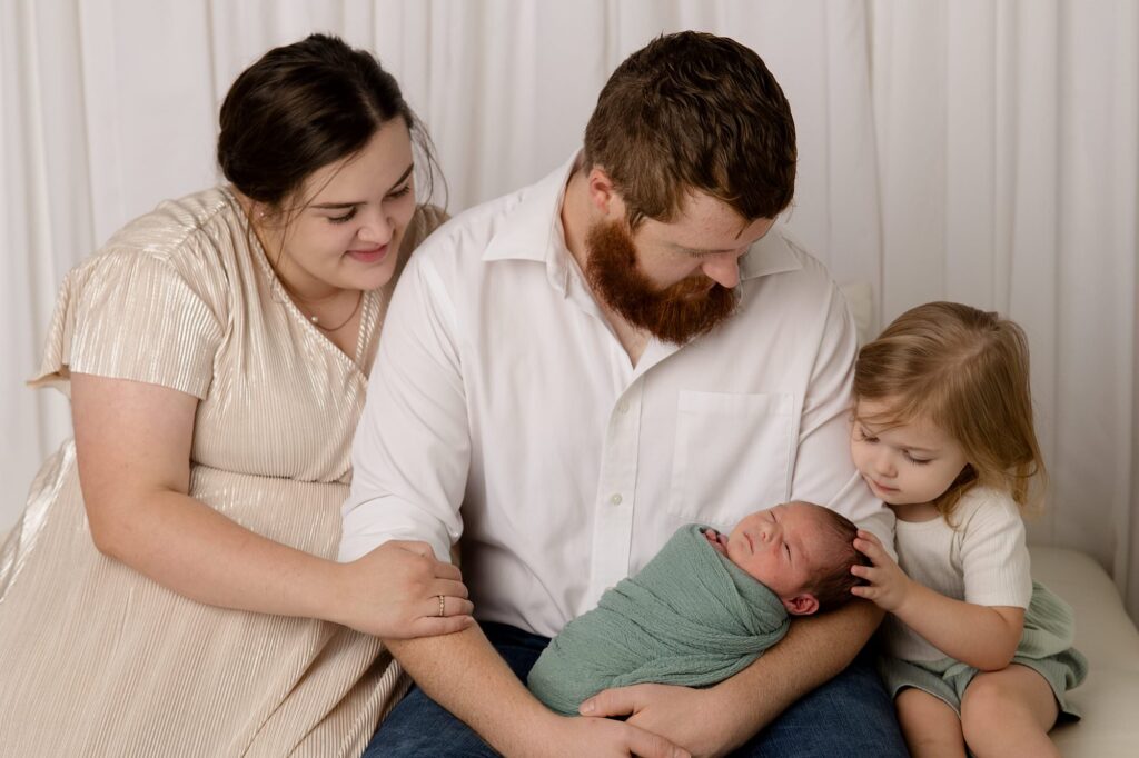 Family of 4 is sitting during this studio newborn session. Captured by Mary Wiebe Photography.