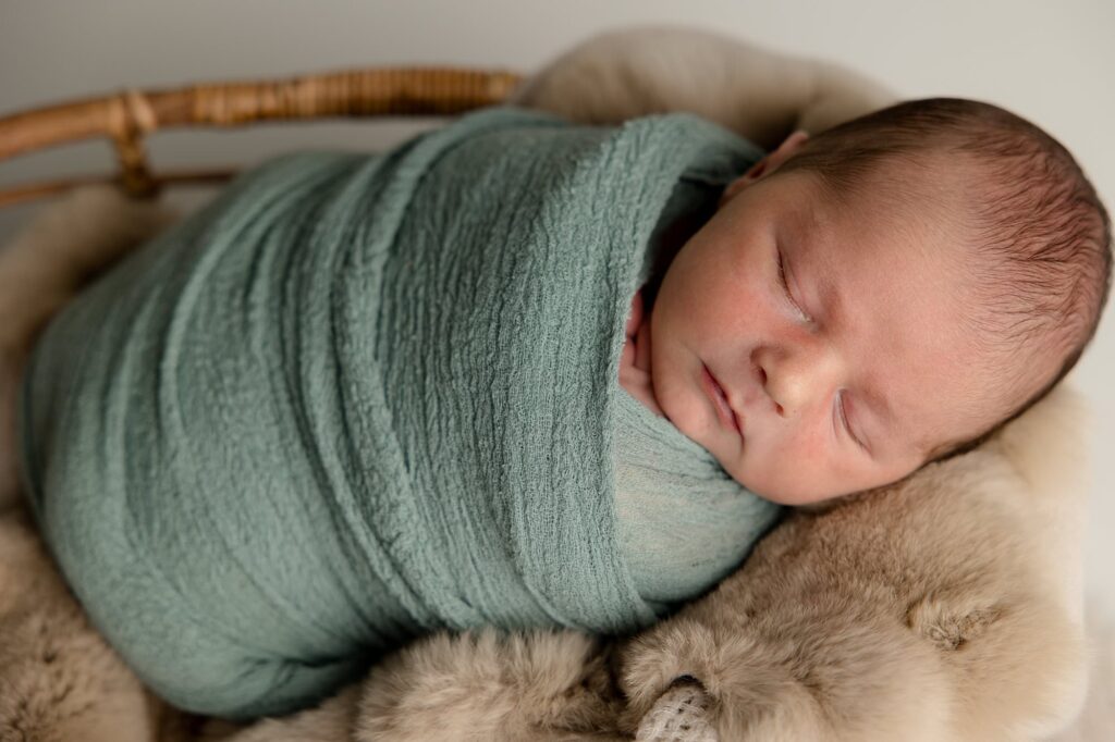 Baby boy sleeping while swaddled up.