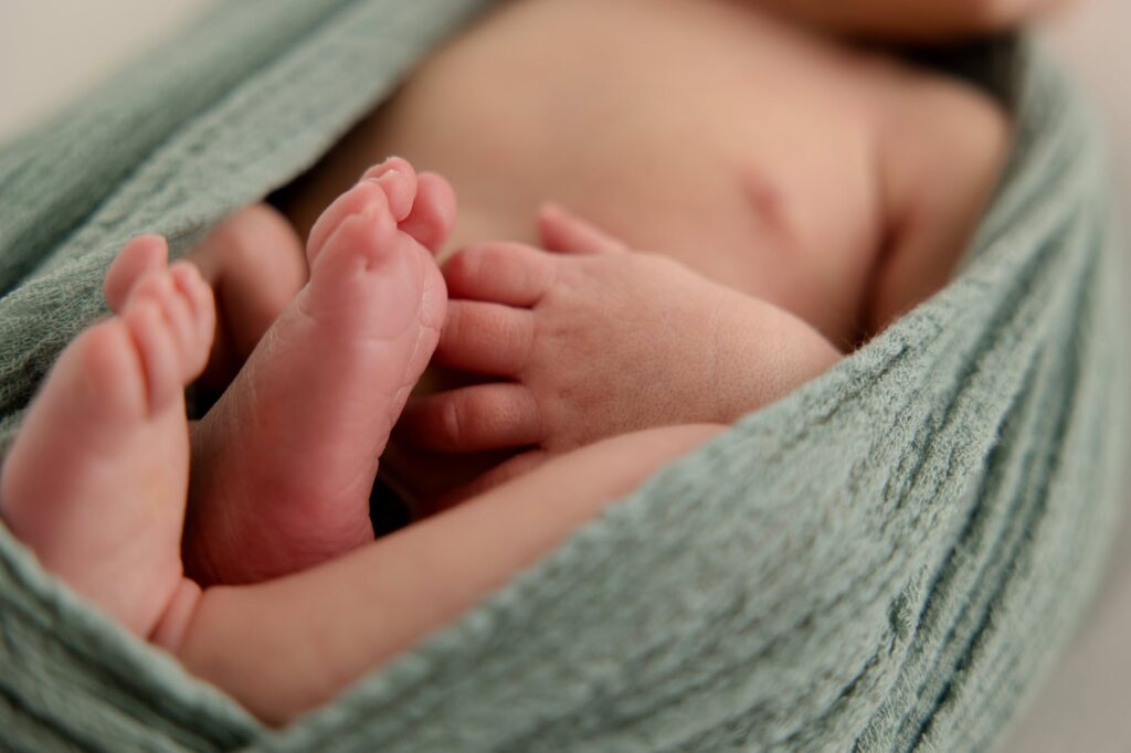 Close up of baby boy's feet in green blanket during studio newborn session.