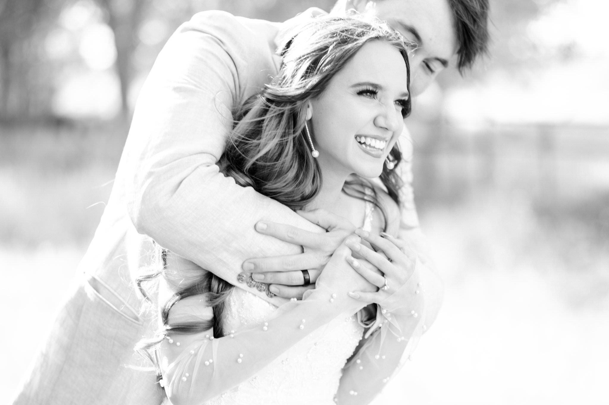 Black & white image of bride and groom embracing.