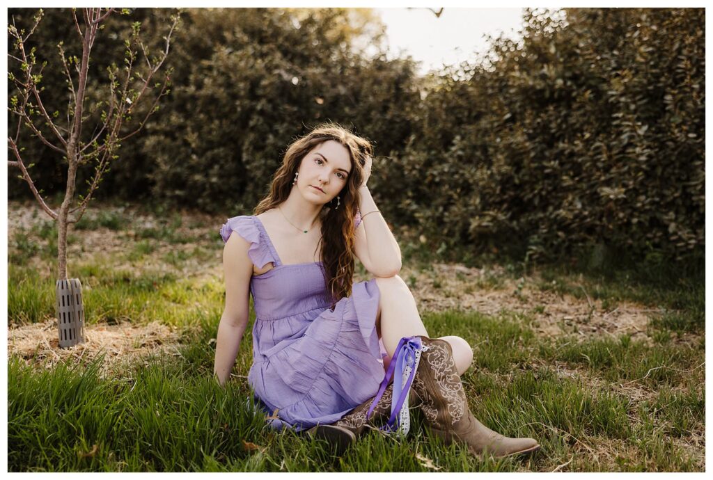 senior girl prepping for school photos in her purple dress posing in grass for senior lubbock photographer Mary Wiebe Photographer

