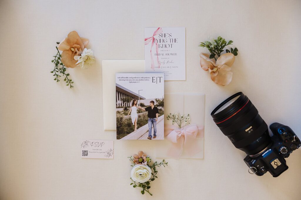 Wedding invitations with flowers beside and Mary Wiebe Lubbock Photography's camera
