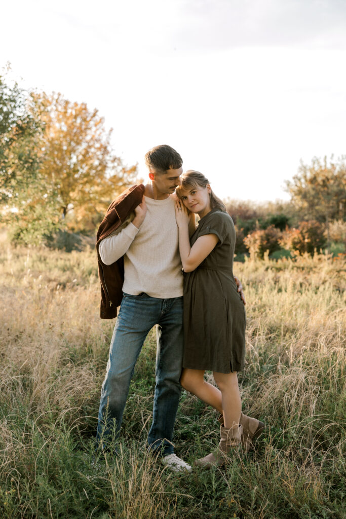 gorgeous sunset photo of a young couple standing in a grass field.