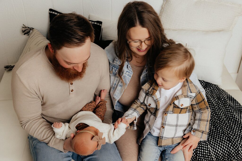 Lubbock family huddled on the couch admiring the newborn. Captured by Mary Wiebe Photography. 