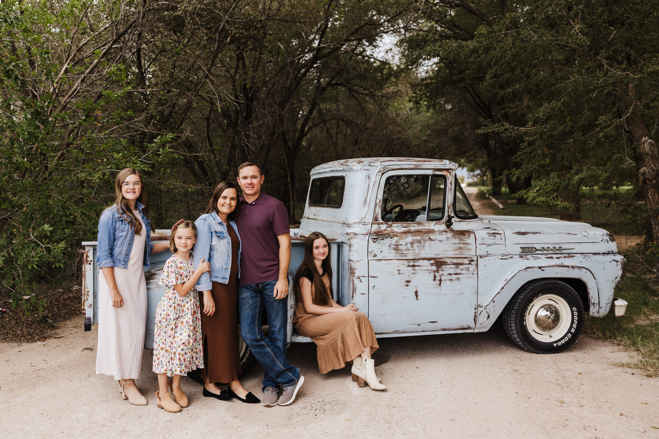 Denver City Texas Photographer photographs a family of five in front of an old blue truck at Mustang Park in Denver City, Texas. Photo taken by Mary Wiebe, a Lubbock family photographer