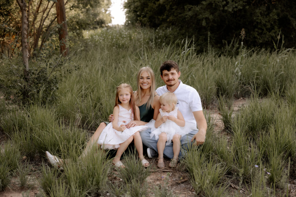 A family, stress-free session captured by Mary Wiebe, a Lubbock family photographer. Family of four sitting on the ground holding each other. 