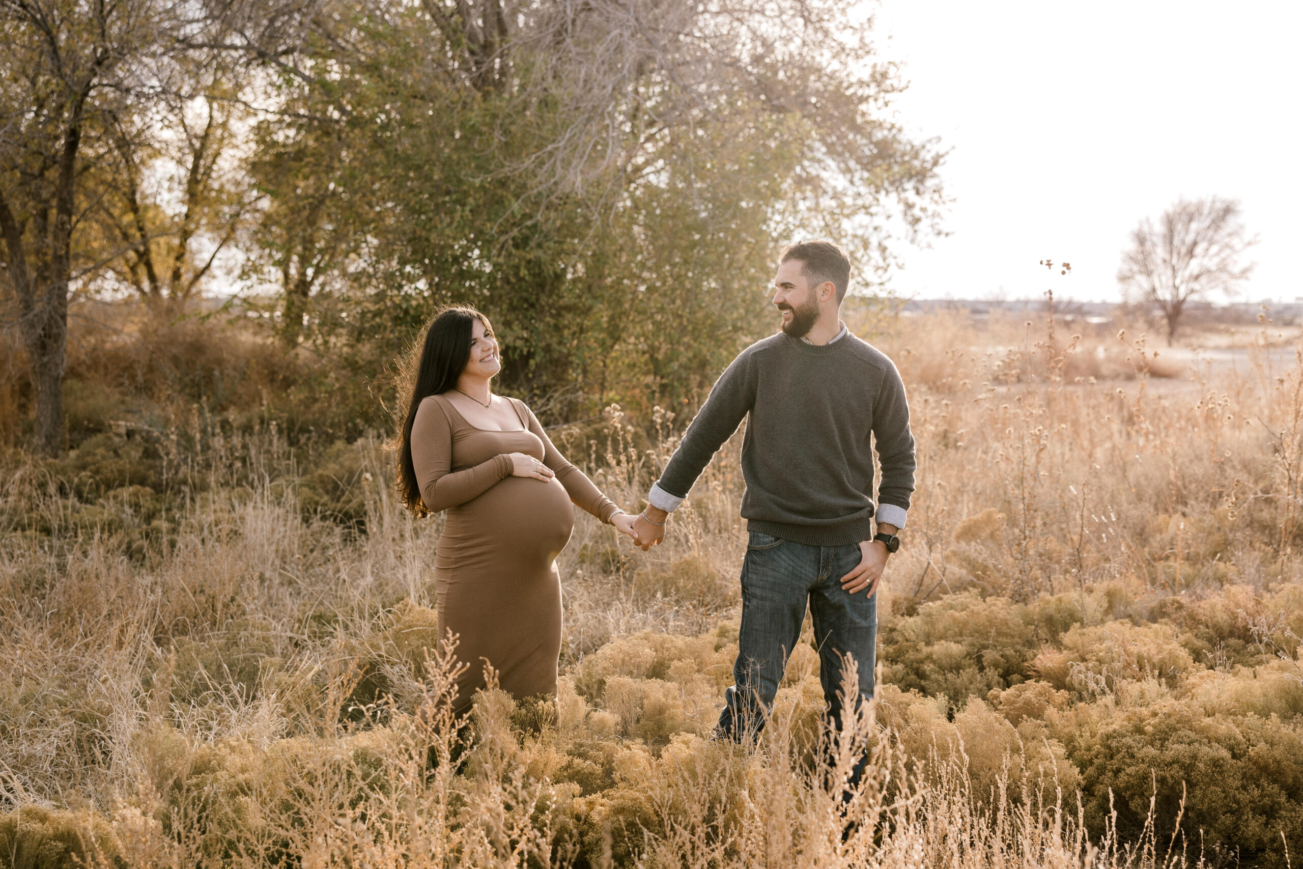 Maternity session captured by Lubbock, Texas photographer Mary Wiebe. Mom is holding her stomach with one hand and with the other is holding her husbands hand.