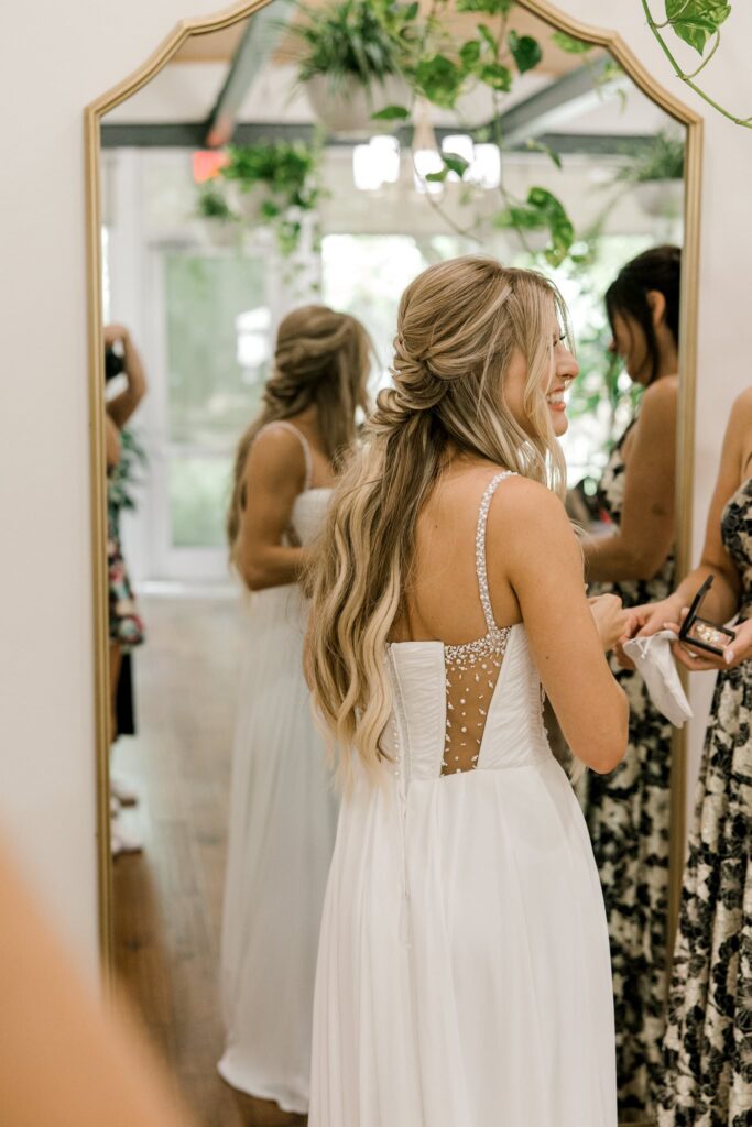 Bride's mom helping bride get into dress at the venue.