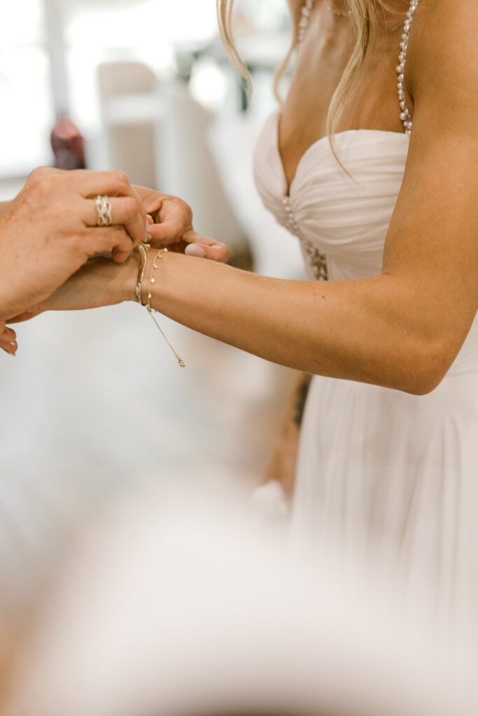 Mother of the bride is closing a bracelet for the bride.