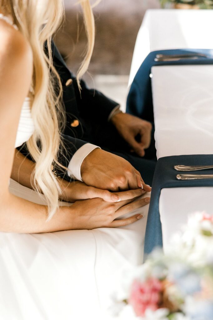 Bride and groom holding hands during the meal prayer