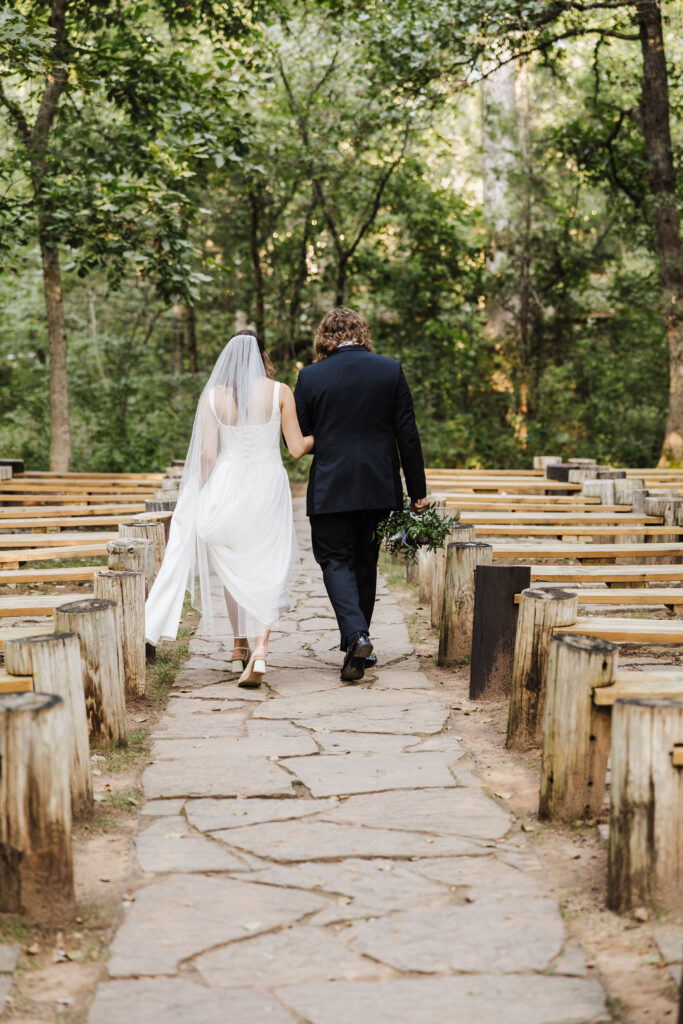Bride and groom walking to their ceremony location, arms are linked. Merrick Hollow Wedding venue