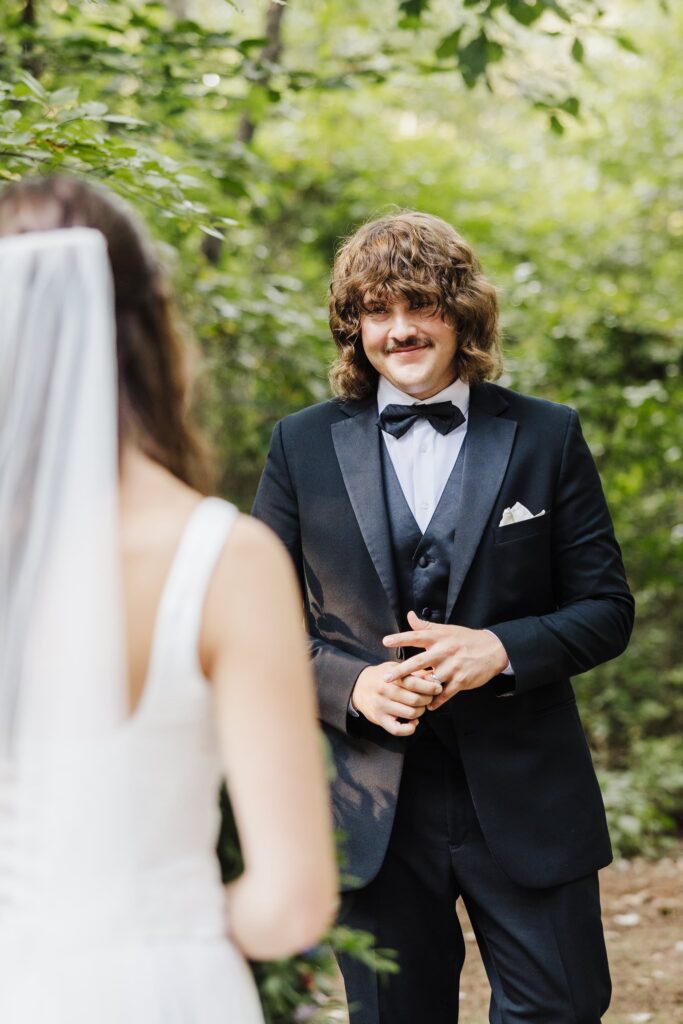 Groom turning around and seeing bride for the first time, groom has a soft smile on his face.