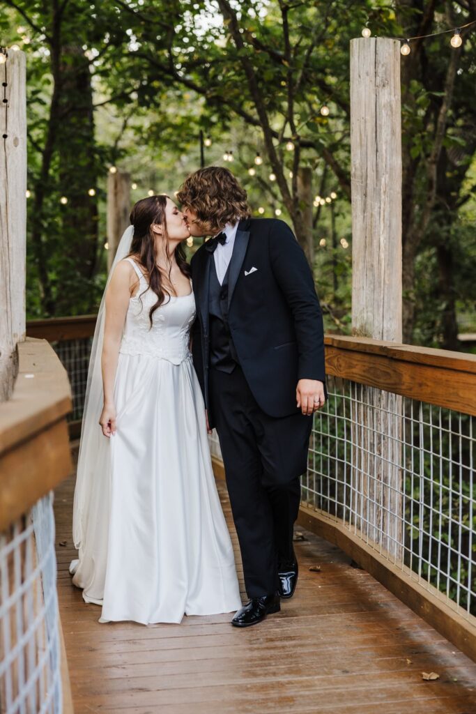 Bride and groom kissing on the walkway to the venue. Merrick Hollow Wedding venue
