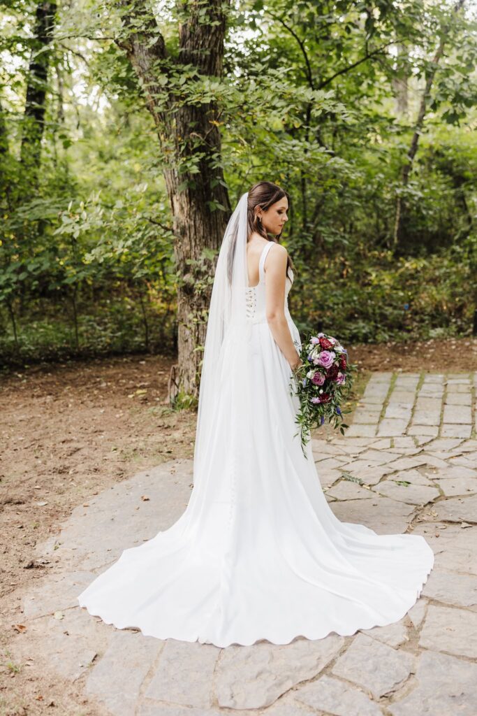 Stunning portrait of the back of the brides dress and veil, at the ceremony location at Merrick Hollow.
