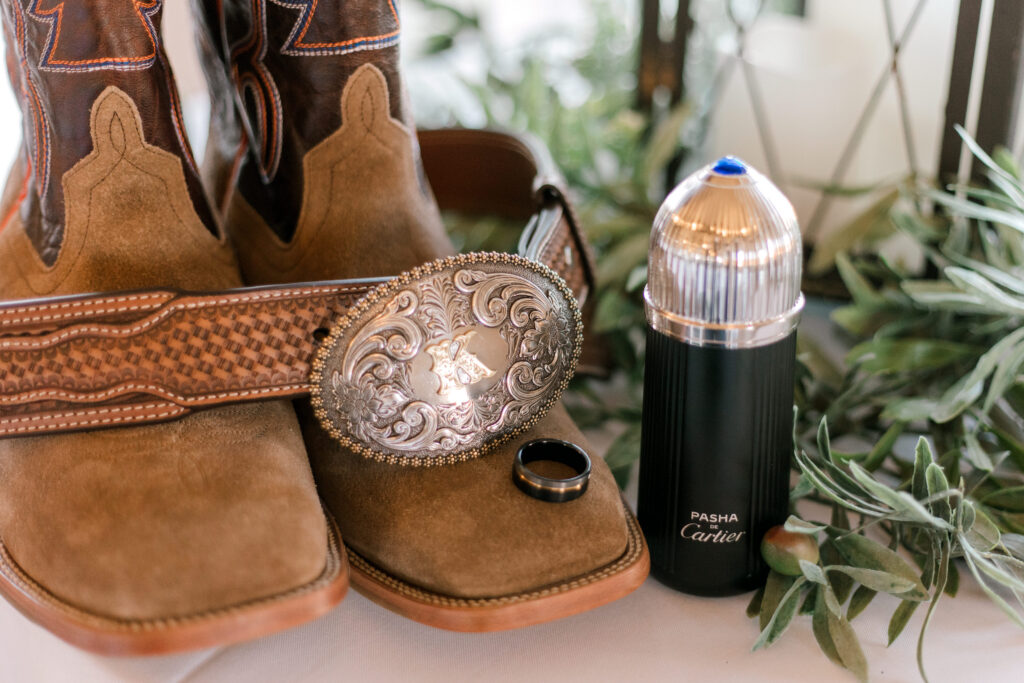 groom details of ring, cologne, boots and belt buckly