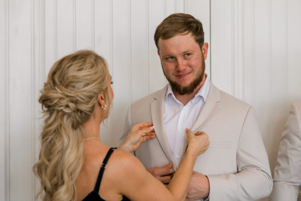 Mother of the groom fixing his jacket before first look.