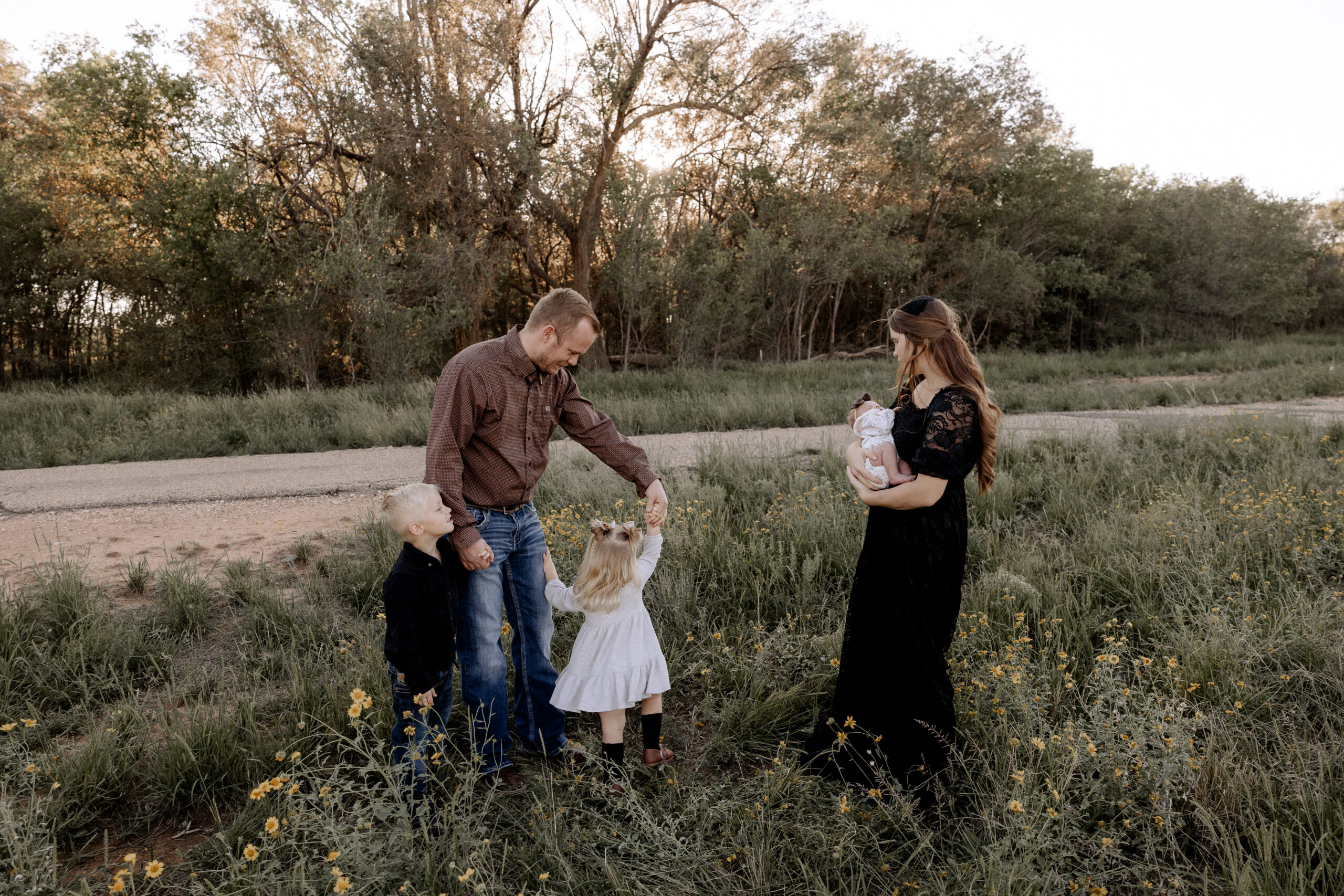 This outdoor newborn session captured by Mary Wiebe in West Texas where mom is holding baby, and dad is holding hands with his two children.