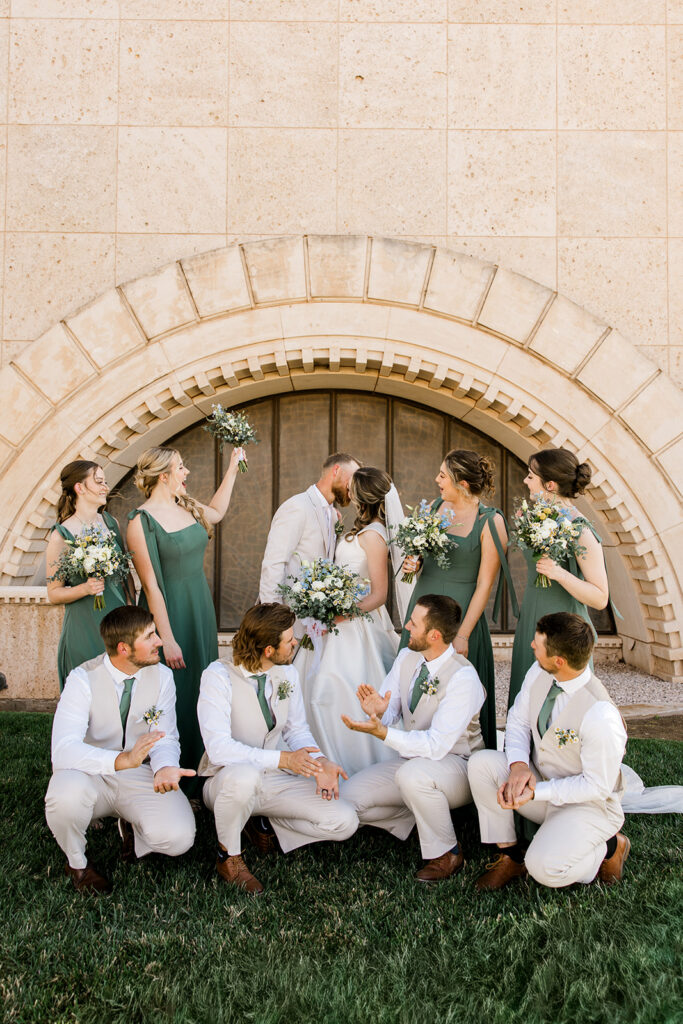 Seminole Texas wedding at the MS Doss chapel. Bride and groom are kissing and the bridal party is standing around them cheering.