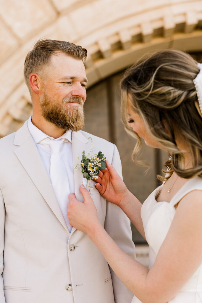 Bride pinning on the boutonnière for the groom. 