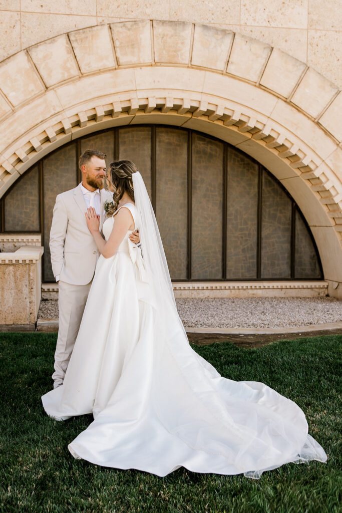 Bride and groom standing side by side looking and smiling at each other.