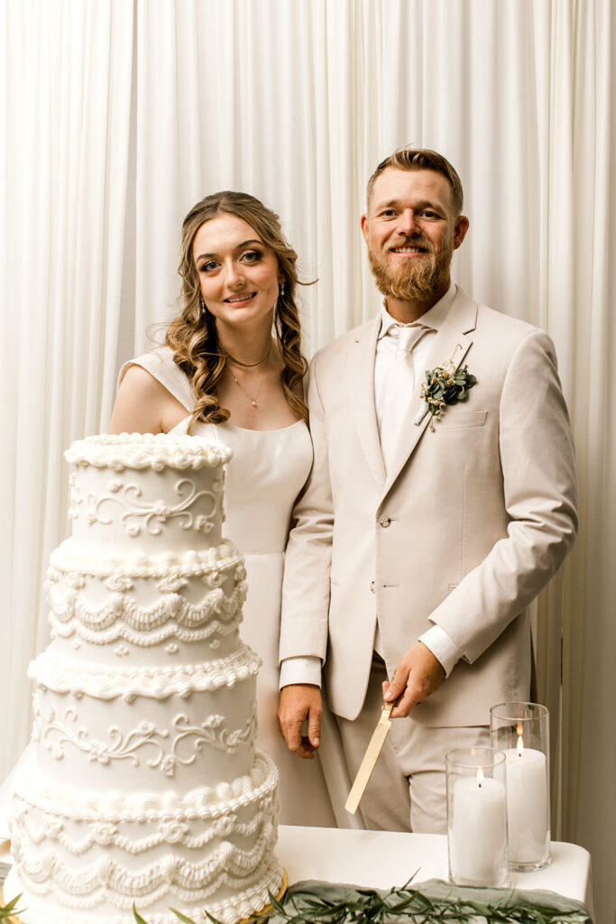 Bride and groom standing behind their cake.