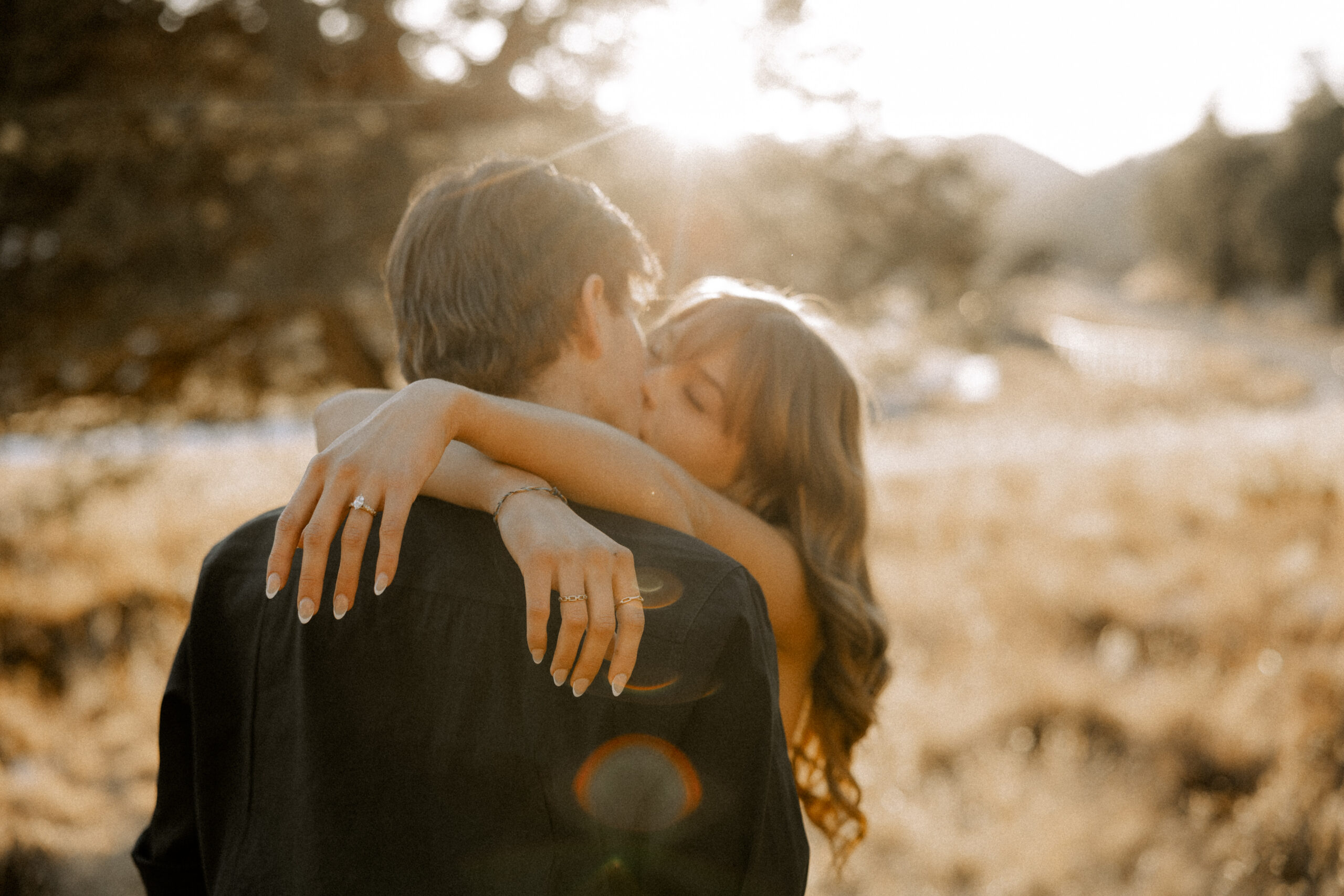 A Lubbock, TX engagement session, captured by Mary Wiebe Photography. This couple embracing in a kiss. Her arms are wrapped around his shoulders during golden hour.