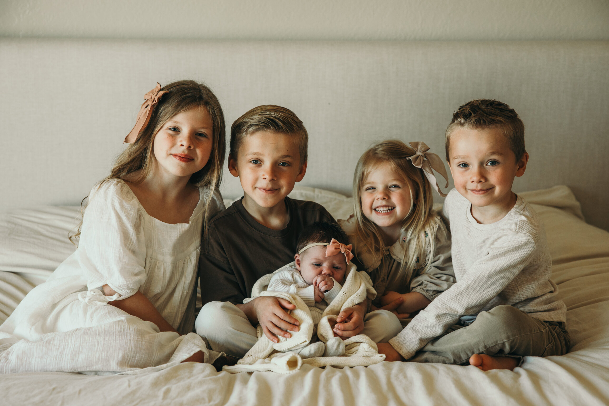 Learning how to prepare siblings for a newborn session can be hard. In this image 4 siblings gather around their newborn sister. Captured by Mary Wiebe Photography.