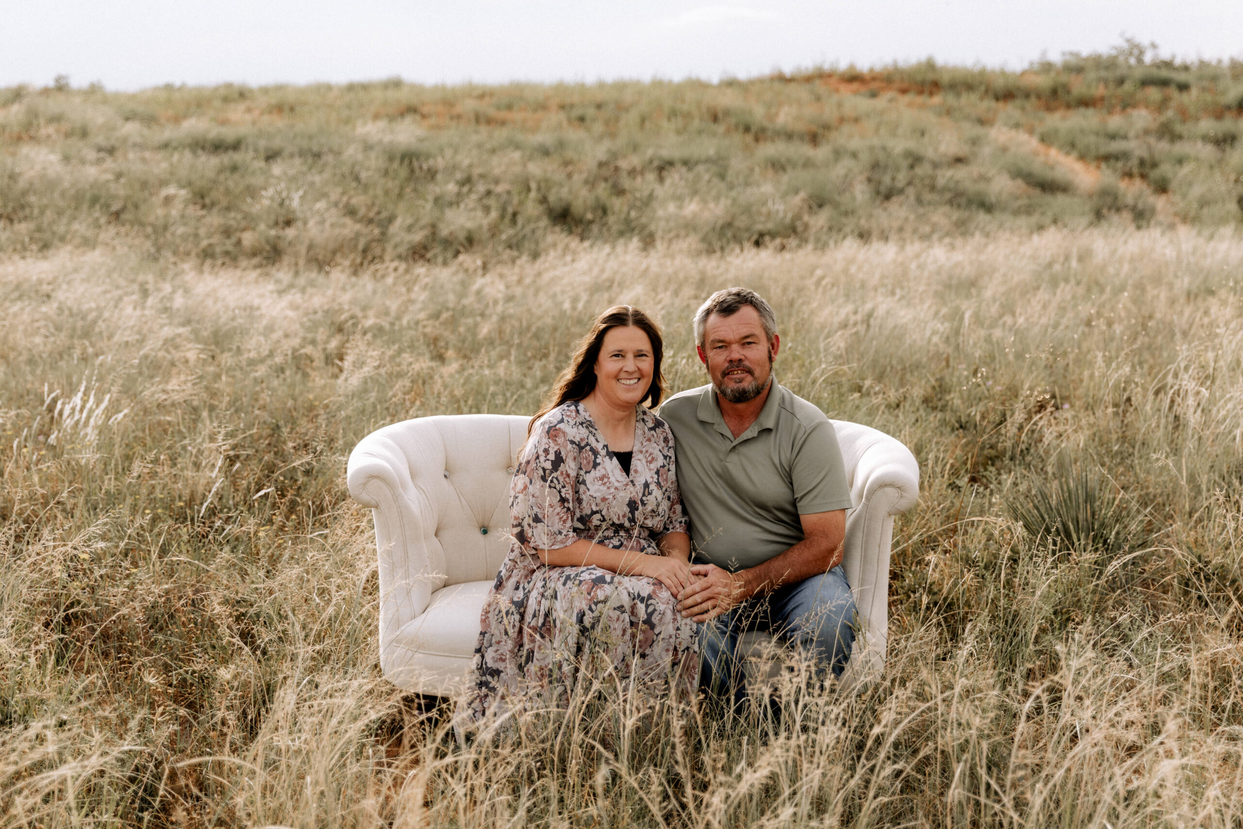Mary Wiebe with her husband Abe. They are sitting on a bench in a grass field.