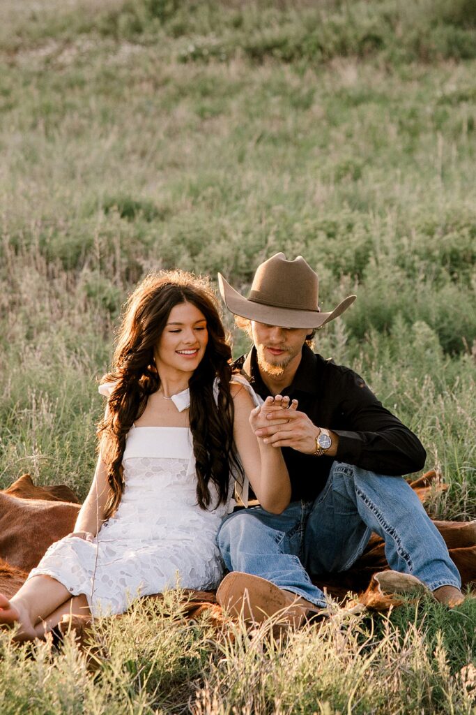 Future bride and groom are looking at her ring during this engagement session. 