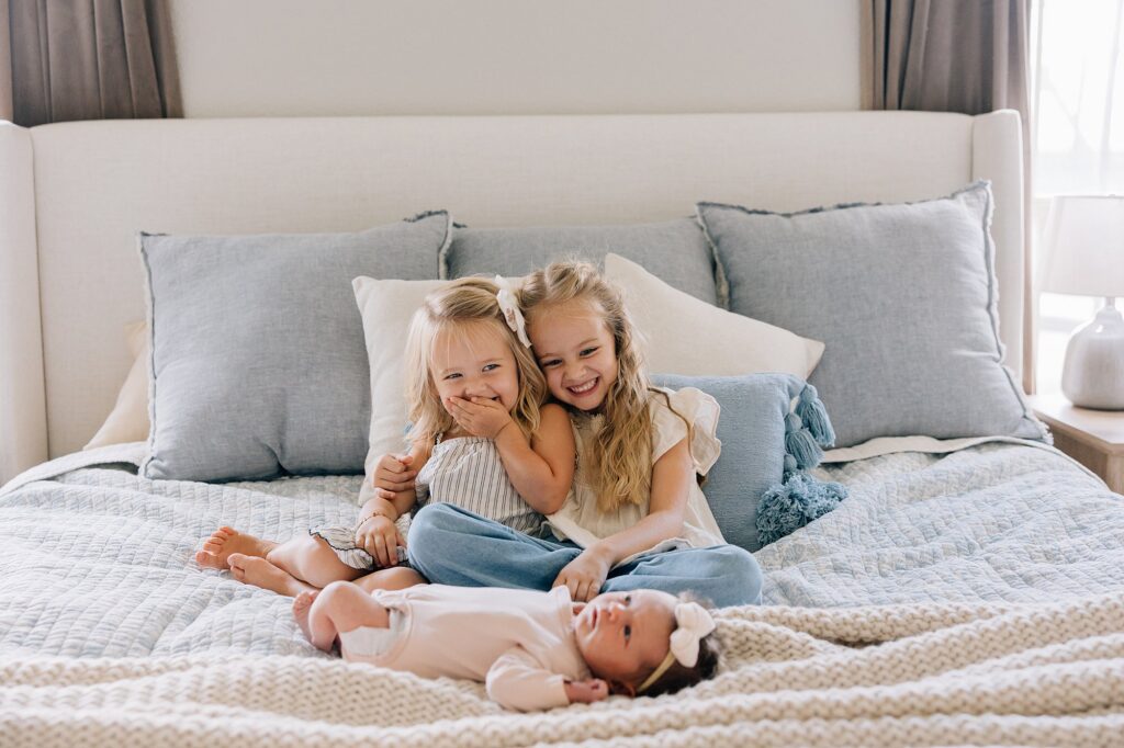 Three sisters are laughing in their parents' bed. 