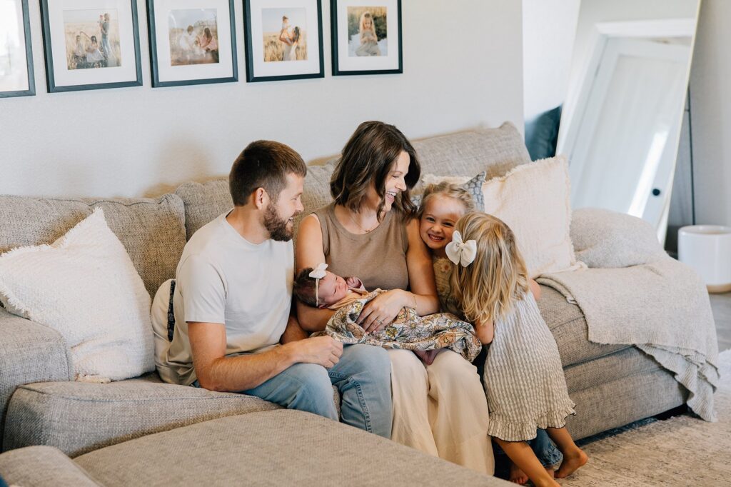 Family of 5 is at a newborn lifestyle session in Lubbock. They are sitting on their couch, captured by Mary Wiebe Photography. 