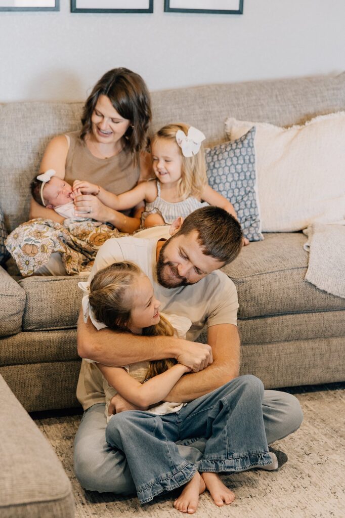 Family of 5 is at a newborn lifestyle session in Lubbock. They are sitting on their couch, captured by Mary Wiebe Photography. 