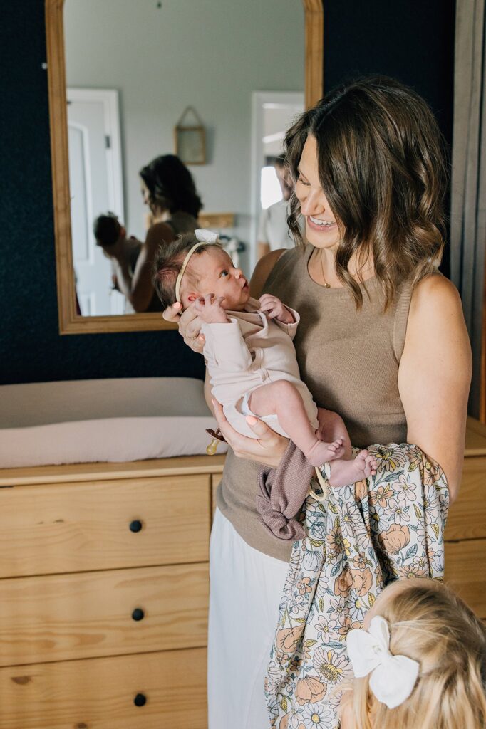 Mama is holding her newborn and smiling. 
