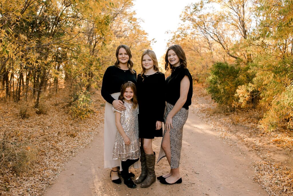 Mom and daughters embracing each other during the fall. 