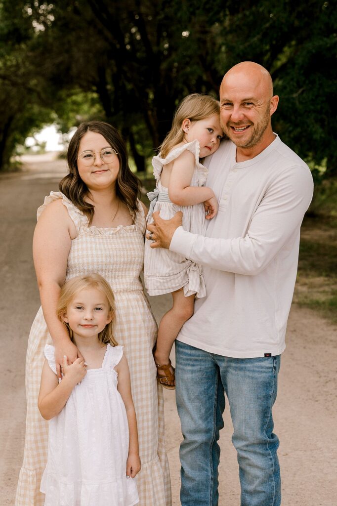 Family of four standing by trees during this family photo session.
