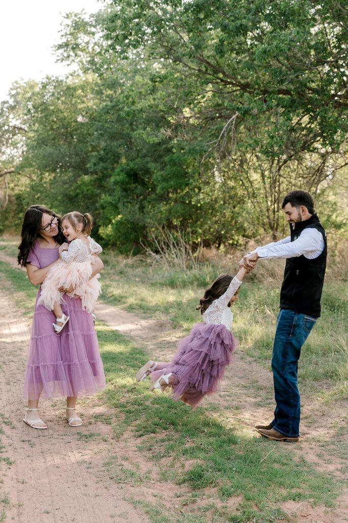 Mom holding baby, and dad swinging his oldest daughter.