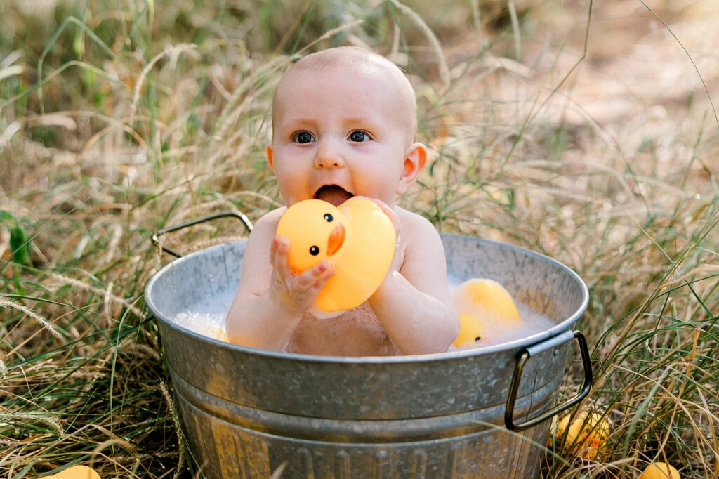 Baby boy sitting in a bubble bath in the grass. 