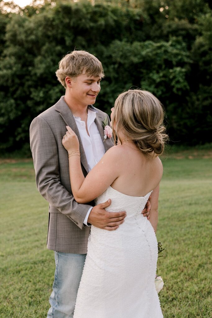 This bride and groom was captured by Mary Wiebe Photography, a Guthrie wedding photographer, standing in a green field holding each other.