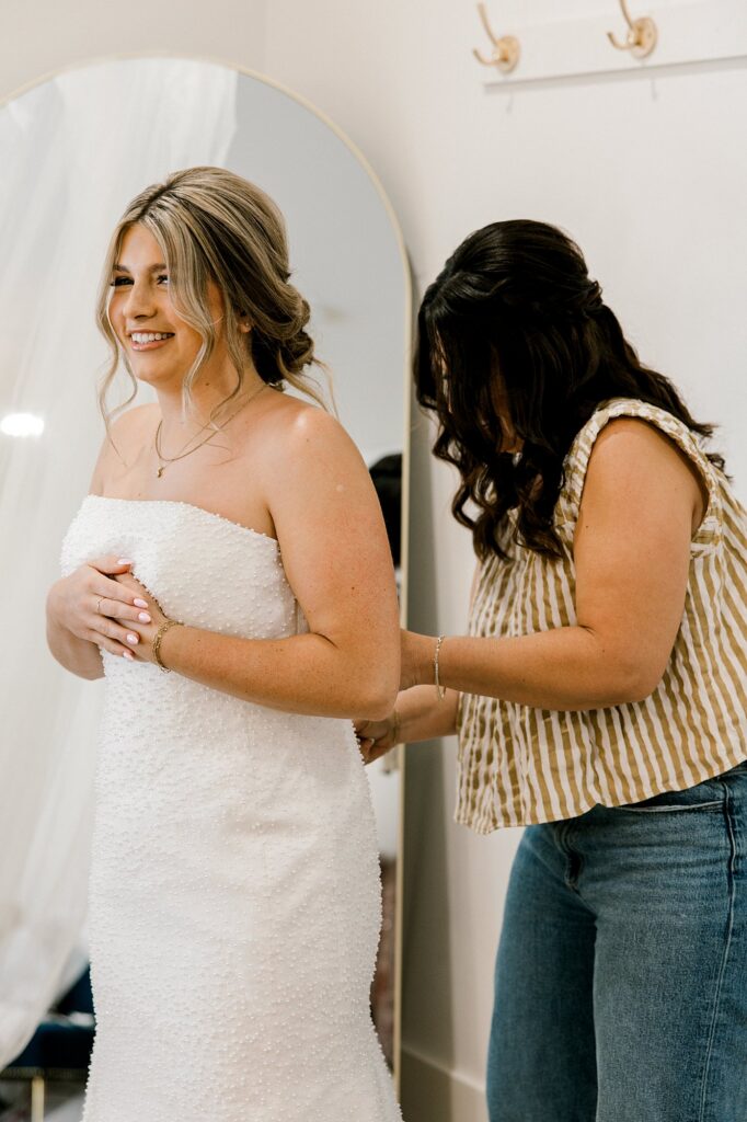 Mom helping bride into dress. By Mary Wiebe Photography.