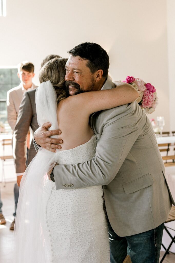 Bride and father share a hug. Captured by Mary Wiebe Photography.