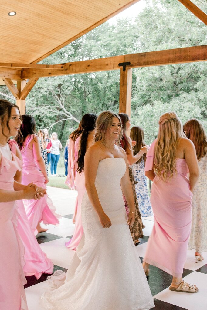 Bride is dancing with her bridesmaids. Captured by Mary Wiebe Photography.