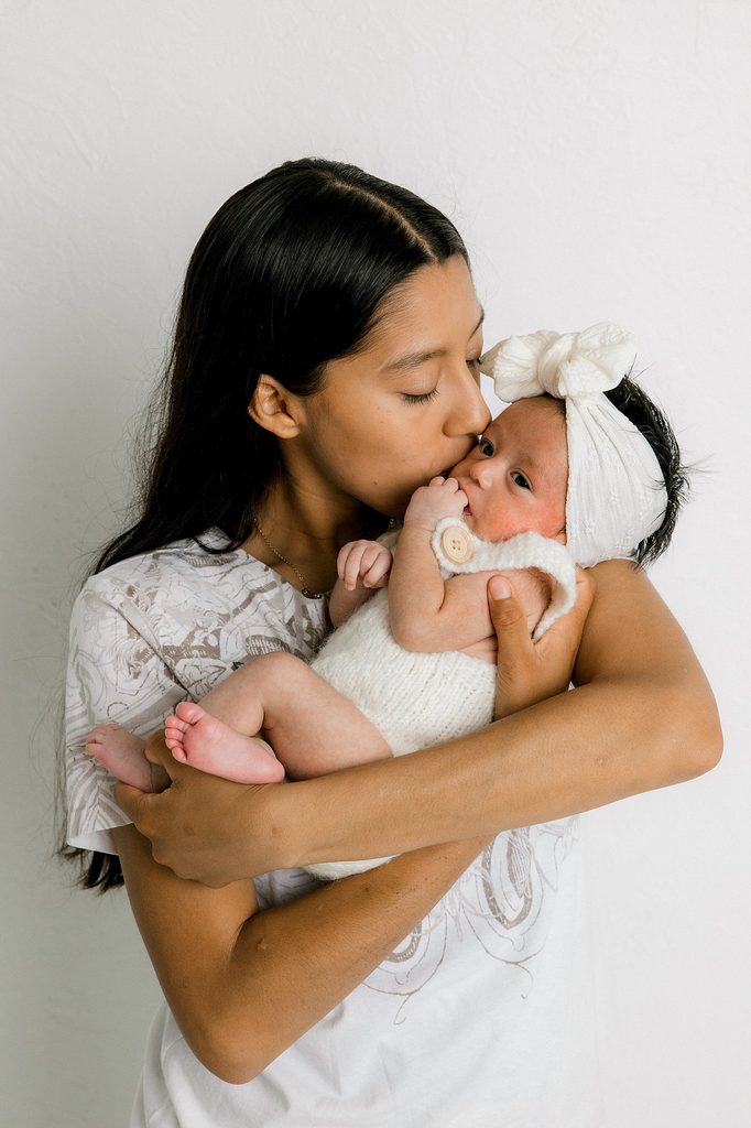 Mama holding her newborn daughter closely to her face. 