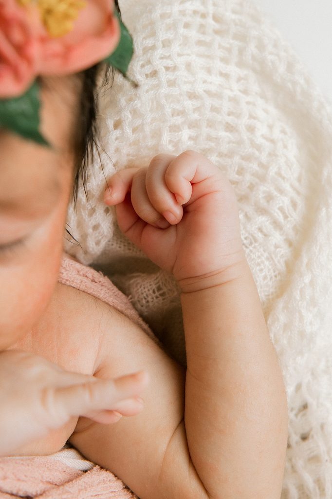 Detail shot of newborn girl's hand on a while blanket. 