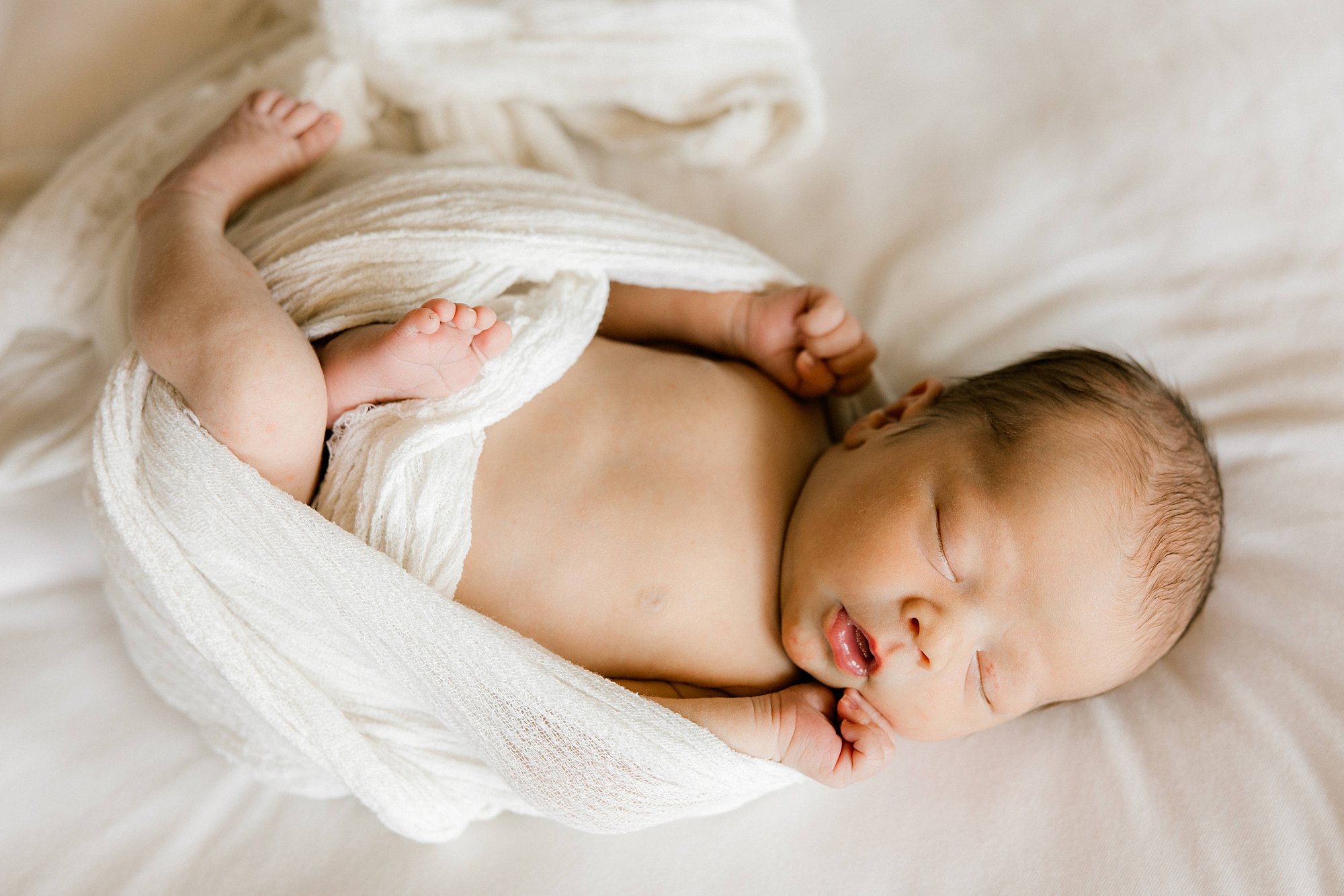Newborn baby asleep in a cream swaddle during an in-home newborn session in Lubbock, TX. Mary Wiebe shows us what to bring to your newborn session.