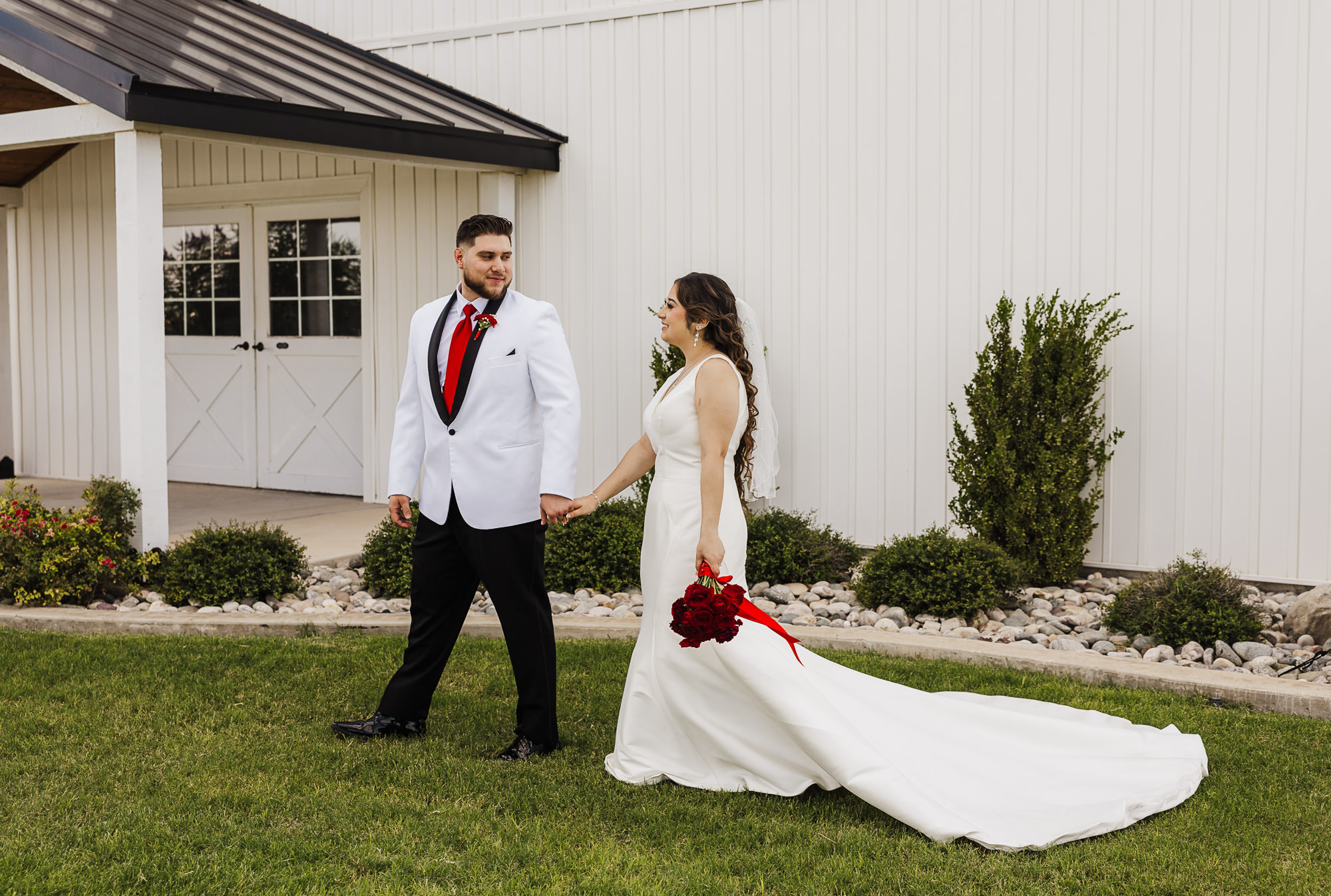 Bride and groom looking at each other with a red rose bouquet