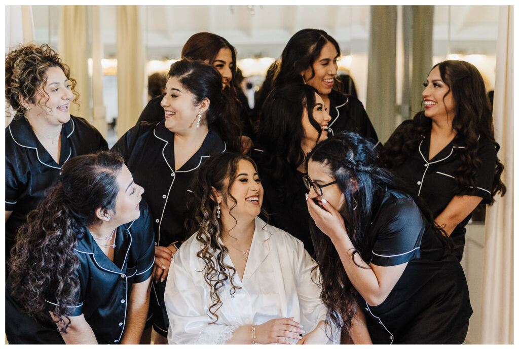 Bridesmaids share a moment captured by Mary Wiebe Photography of Seminole, Texas with girls giggling in robes while getting ready